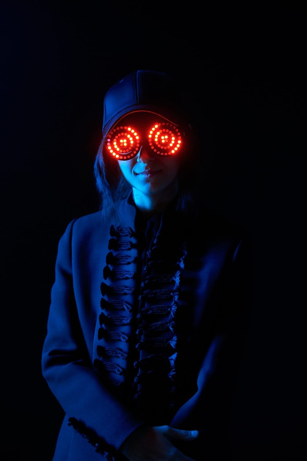 a person wearing a hat and red lights on their glasses